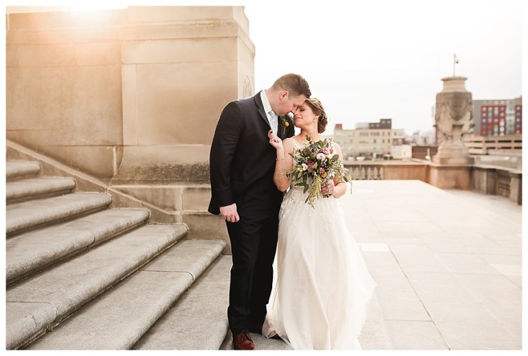 bride and groom leaning into each other in soft sunlight in city