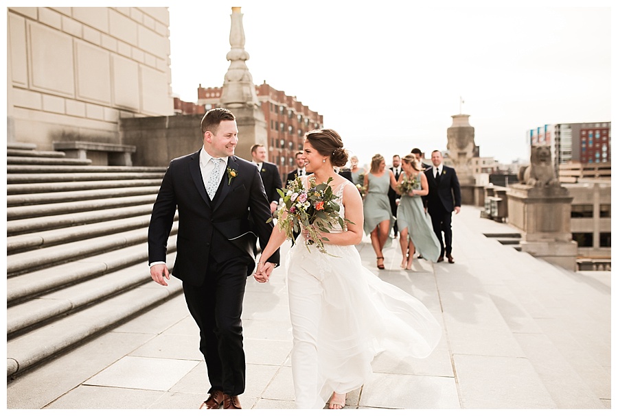 wedding party walking behind bride and groom with city skyline
