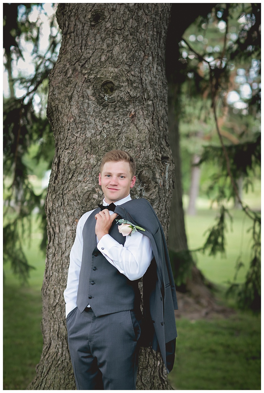 groom smiling and holding jacket over shoulder